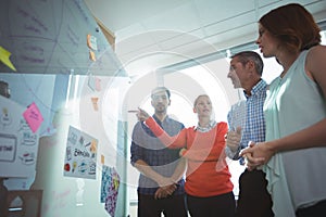 Low angle view of business colleagues discussing over whiteboard at office