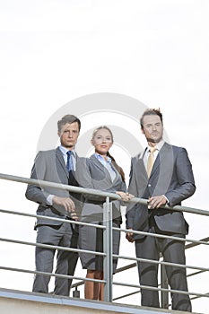 Low angle view of businesspeople standing on terrace against clear sky