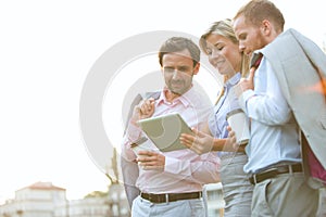 Low angle view of businesspeople using digital tablet against clear sky