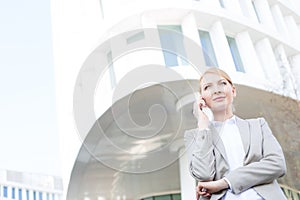 Low angle view of businesswoman using cell phone outside office building