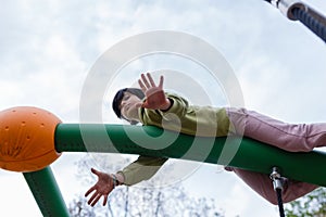 low angle view of child hanging on crossbar at playground