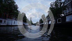 Low angle view of city canal with houseboats at twilight in Amsterdam