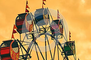 Low angle view of colorful Ferris Wheel cabins in an amusement park during the evening