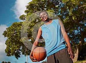 Low angle view of a confident male basketball player holding ball in hand looking to camera