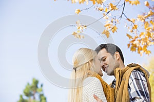 Low angle view of couple kissing against clear sky during autumn