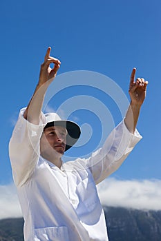 Low angle view of cricket umpire signalling six runs against blue sky