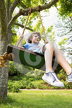 Low angle view of a cute little boy on swing