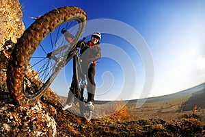 Low angle view of cyclist riding mountain bike on rocky trail at sunrise