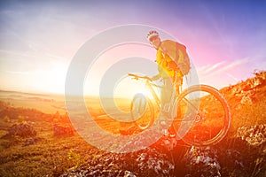 Low angle view of cyclist standing with mountain bike on trail at sunset