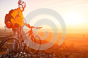 Low angle view of cyclist standing with mountain bike on trail at sunset