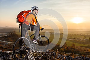 Low angle view of cyclist standing with mountain bike on trail at sunset