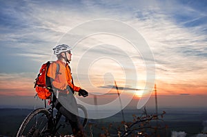 Low angle view of cyclist standing with mountain bike on trail at sunset