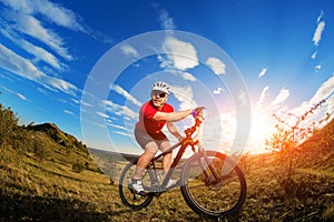 Low angle view of cyclist standing with mountain bike on trail at sunset