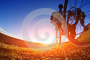 Low angle view of cyclist standing with mountain bike on trail at sunset