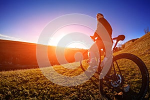 Low angle view of cyclist standing with mountain bike on trail at sunset