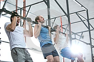 Low angle view of dedicated men doing chin-ups in crossfit gym