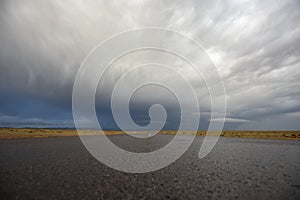 Low angle view of empty road under stormy dramatic sky