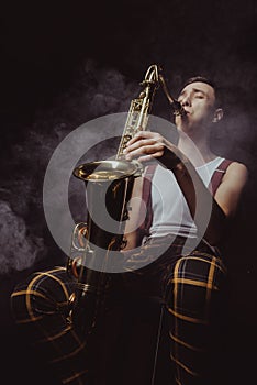 low angle view of expressive young musician playing saxophone in smoke