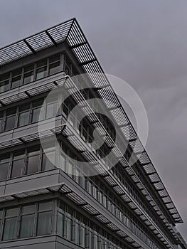 Low angle view of the facade of a modern office building with glass windows and metal elements located in a commercial park.