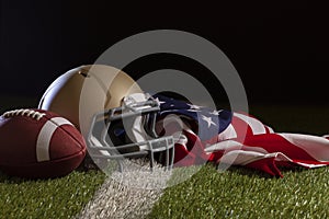 Low angle view of a football and helmet with American flag on a grass field with stripe