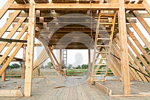 Low angle view of framing members in wood frame home under construction at sunset