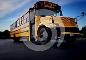 Low angle view of the front door side entrance of a yellow American public school bus used to transport kids to school, field