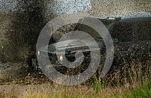 Low angle view of front of SUV on mountain road. Water splash in off road racing. Off-road 4x4 concept. Wheel close up