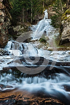 Low angle view of a frozen waterfall surrounded by trees photo