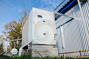 Low angle view of the gray industrial cooling unit standing outdoor on the ground near to the modern of the factory building