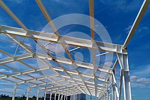 Low angle view of green metal roof of industrial building structure in construction site against blue sky background