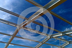 Low angle view of green metal roof of industrial building structure in construction site against blue sky background