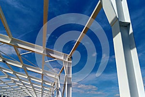 Low angle view of green metal roof of industrial building structure in construction site against blue sky background