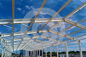 Low angle view of green metal roof of industrial building structure in construction site against blue sky background