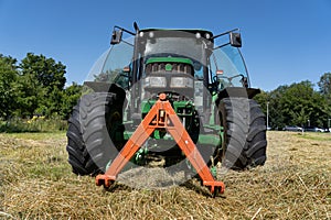Low angle view of green tractor in hay field in summer with open doors