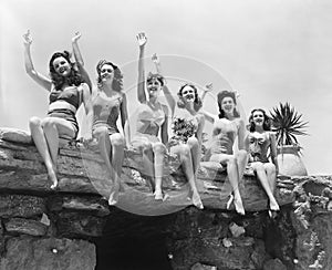 Low angle view of a group of women sitting on a stone structure and waving their hands