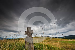 Low angle view of a hand carved old stone cross , dramatic stormclouds
