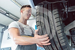 Low-angle view of the hand of a skilled auto mechanic holding a tire