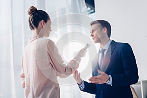 Low angle view of handsome businessman giving interview to journalist with voice recorder