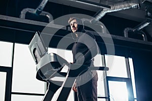 low angle view of handsome sportsman in hoodie exercising on treadmill