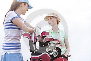 Low angle view of happy female golfers talking against clear sky