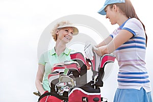 Low angle view of happy female golfers talking against clear sky