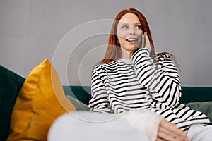 Low-angle view of happy young woman with broken arm wrapped in gypsum bandage talking on smartphone with friends during