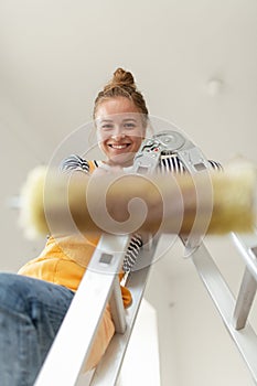 Low angle view of happy young woman remaking her new flat, painting walls. Concept of renovation, indepent women and