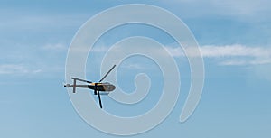 Low angle view of a helicopter flying under a blue sky and sunlight at daytime