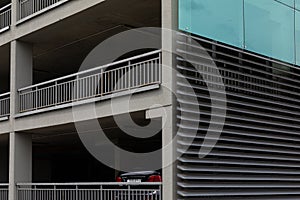 Low angle view of high building facade with metal side wall and concrete front walls with holes.