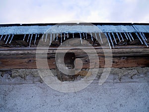 Low angle view of icicles hanging from roof of old rustic barn.