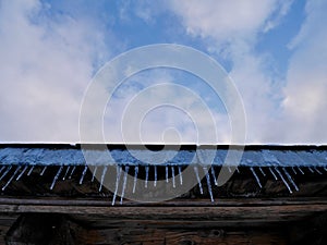 Low angle view of icicles hanging from roof of old wooden barn.