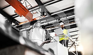 A low angle view of an industrial man engineer with laptop in a factory, working.