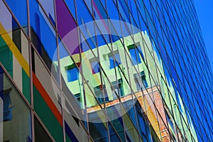 Low angle view on isolated skyscraper glass window facade with reflection of green building