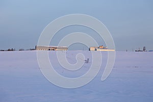 Low angle view of long farm buildings in snowy field seen during a beautiful pink and blue early winter morning, St. Augustin de D